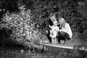 Natural black and white image of family feeding the ducks in local park, lifestyle photograph taken in Beckenham