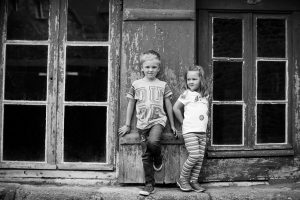 Brother and sister photo in France, leaning against old shop window, taken by Kent photographer