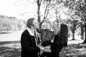 Son tickling dad's face on family photoshoot in London in Beckenham Place Park