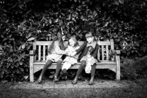 Sisters giggling and tickling each other on a bench in Kelsey Park and taken by Beckenham Photographer