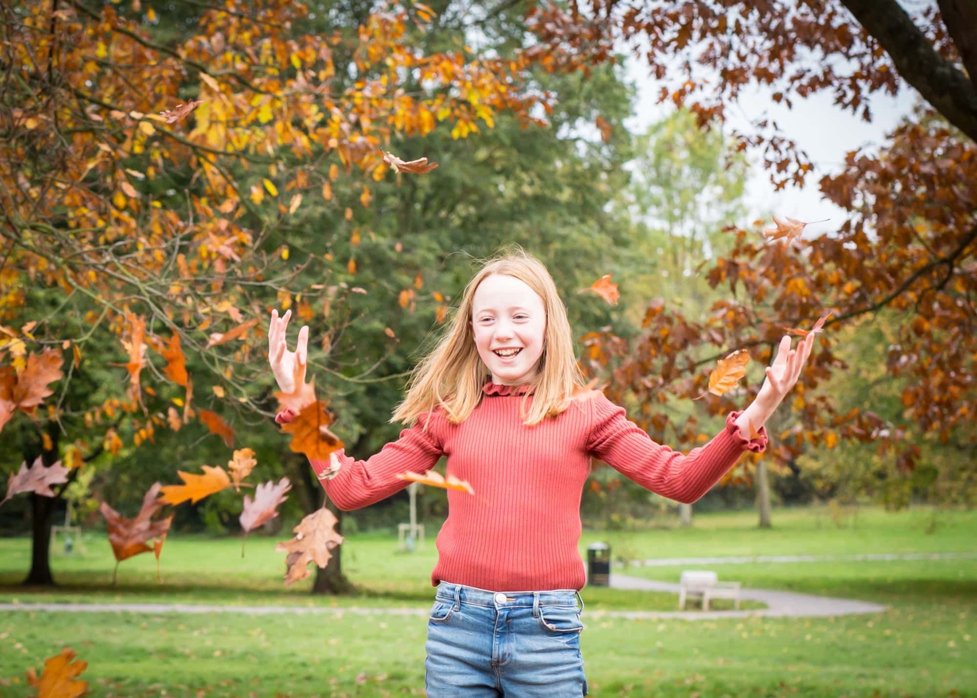 Girl playing in the autumn leaves in park outside in family Bromley photoshoot