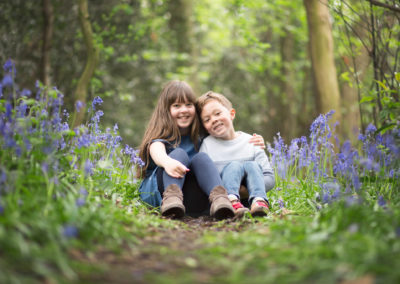 Siblings cuddling in bluebells in park on Bromley photoshoot