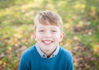 Boy smiling in a park in Autumn taken in Bromley family photoshoot