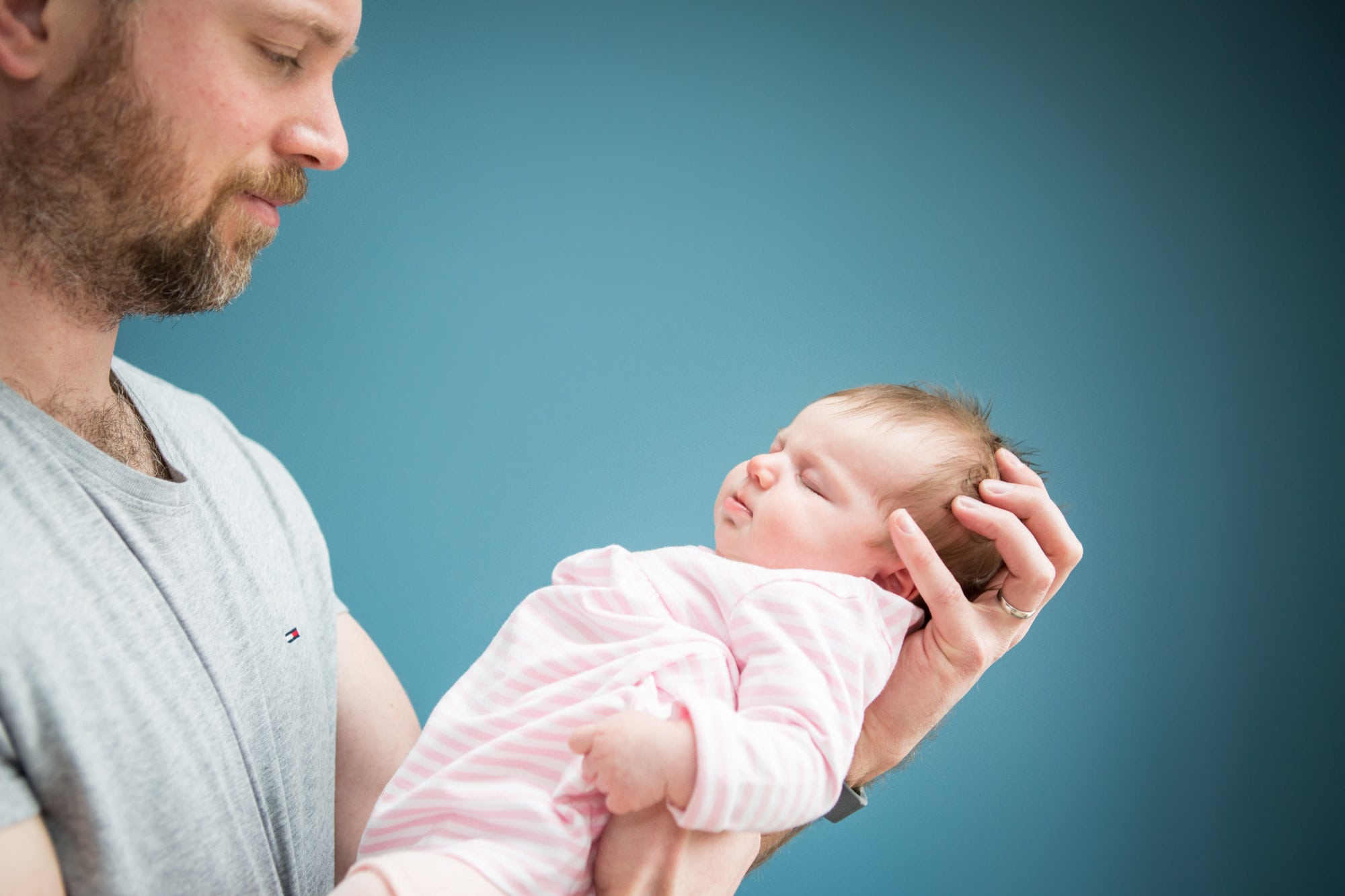 Dad cradling baby daughter in newborn photoshoot in Bromley