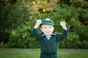 boy in school hat and uniform outside in park