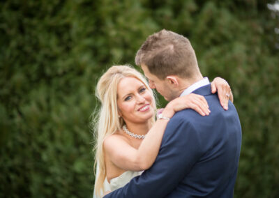 Bride cuddling groom and looking over shoulder in wedding photography in Bromley, Kent