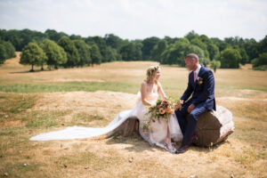 Bride and groom in Beckenham Place Park sitting on log