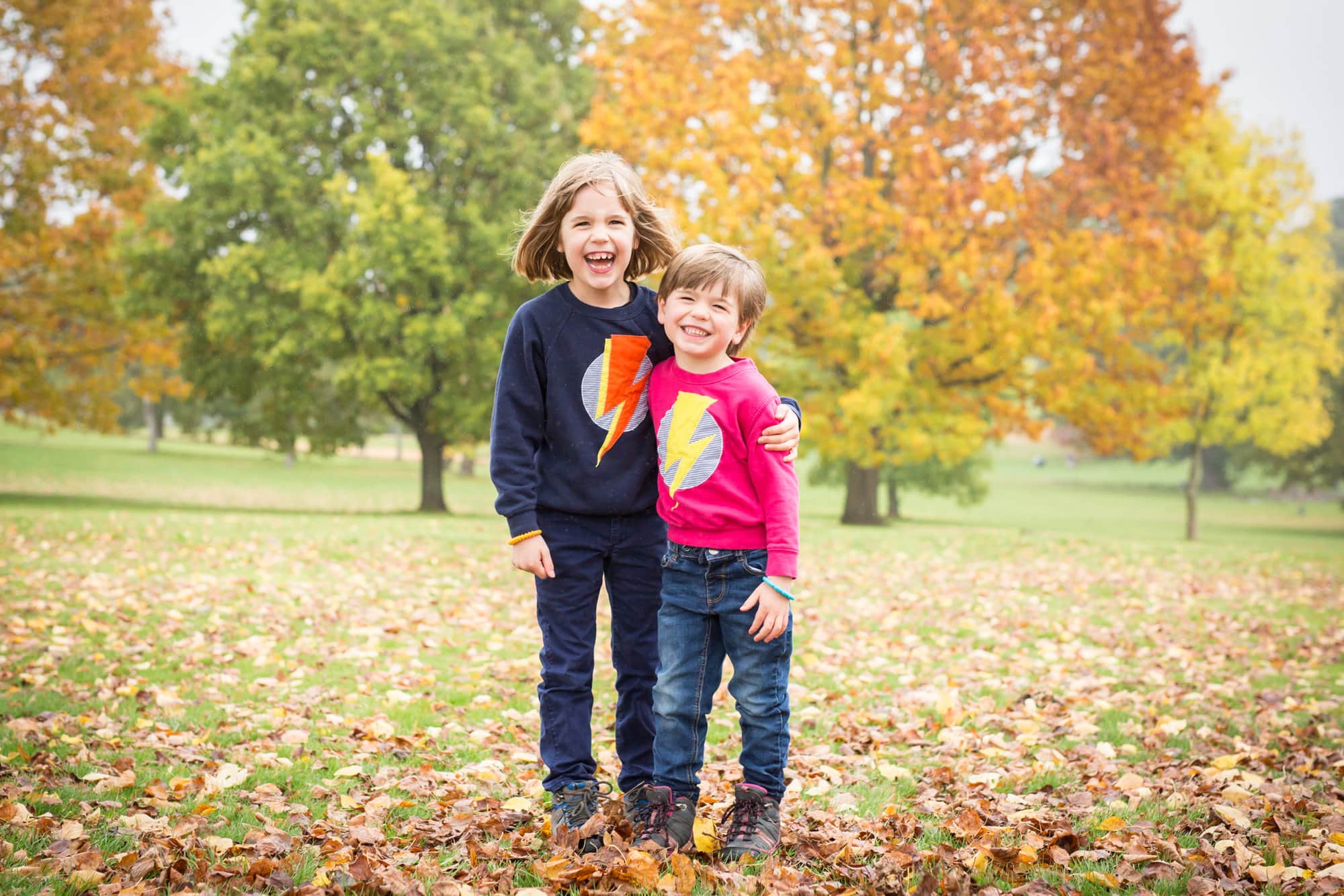 Siblings cuddling in the park in autumn taken by Beckenham photographer