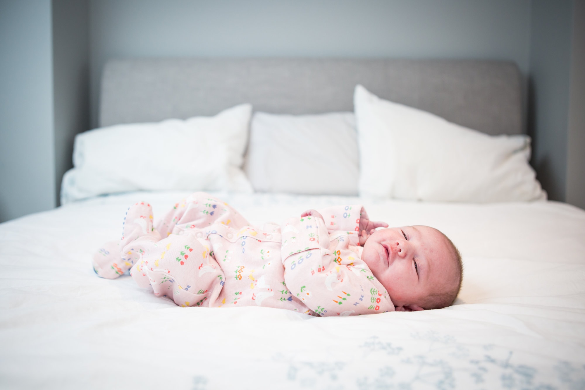 Newborn photoshoot in London with baby curled up on bed