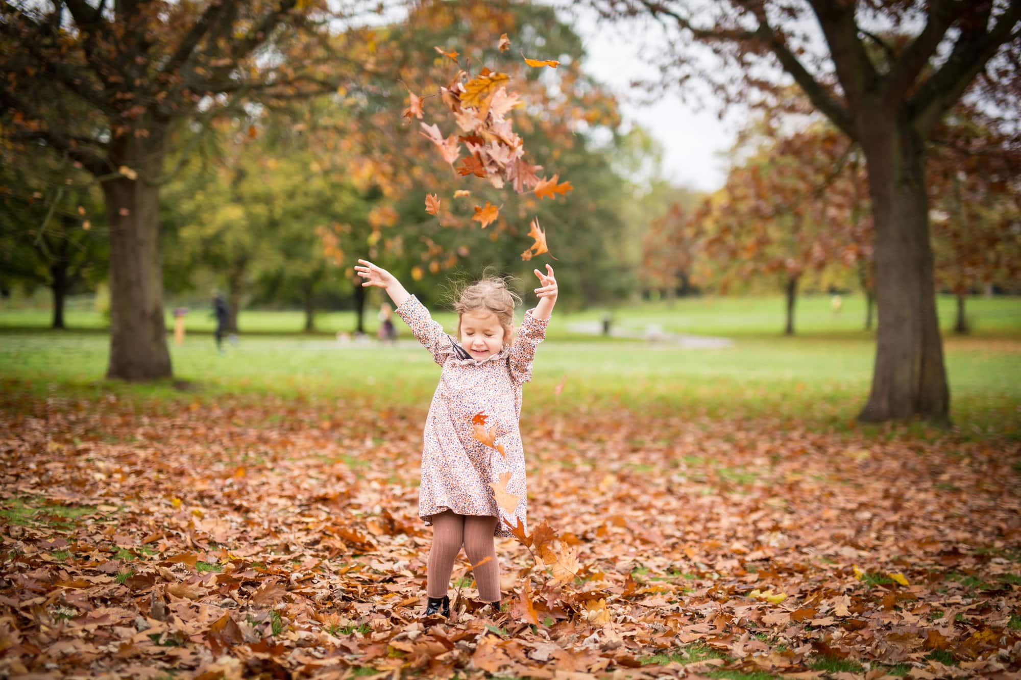 Girl playing in the leaves on family photoshoot in London