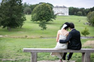 couple sat on bench in wedding photo taken by Beckenham photographer in beckenham place park