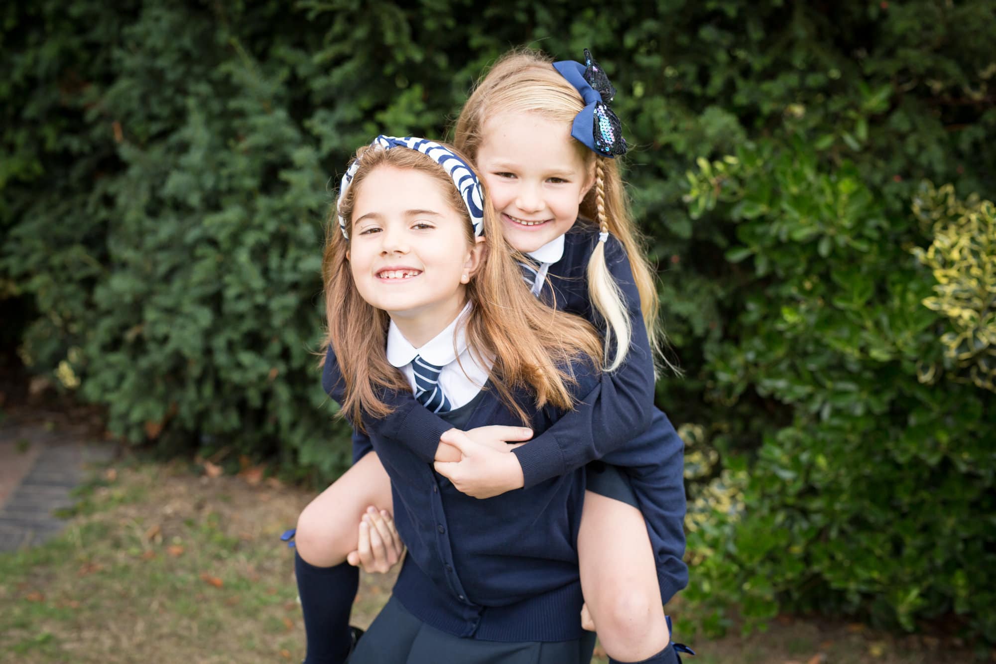 sisters piggy back school photo in the park