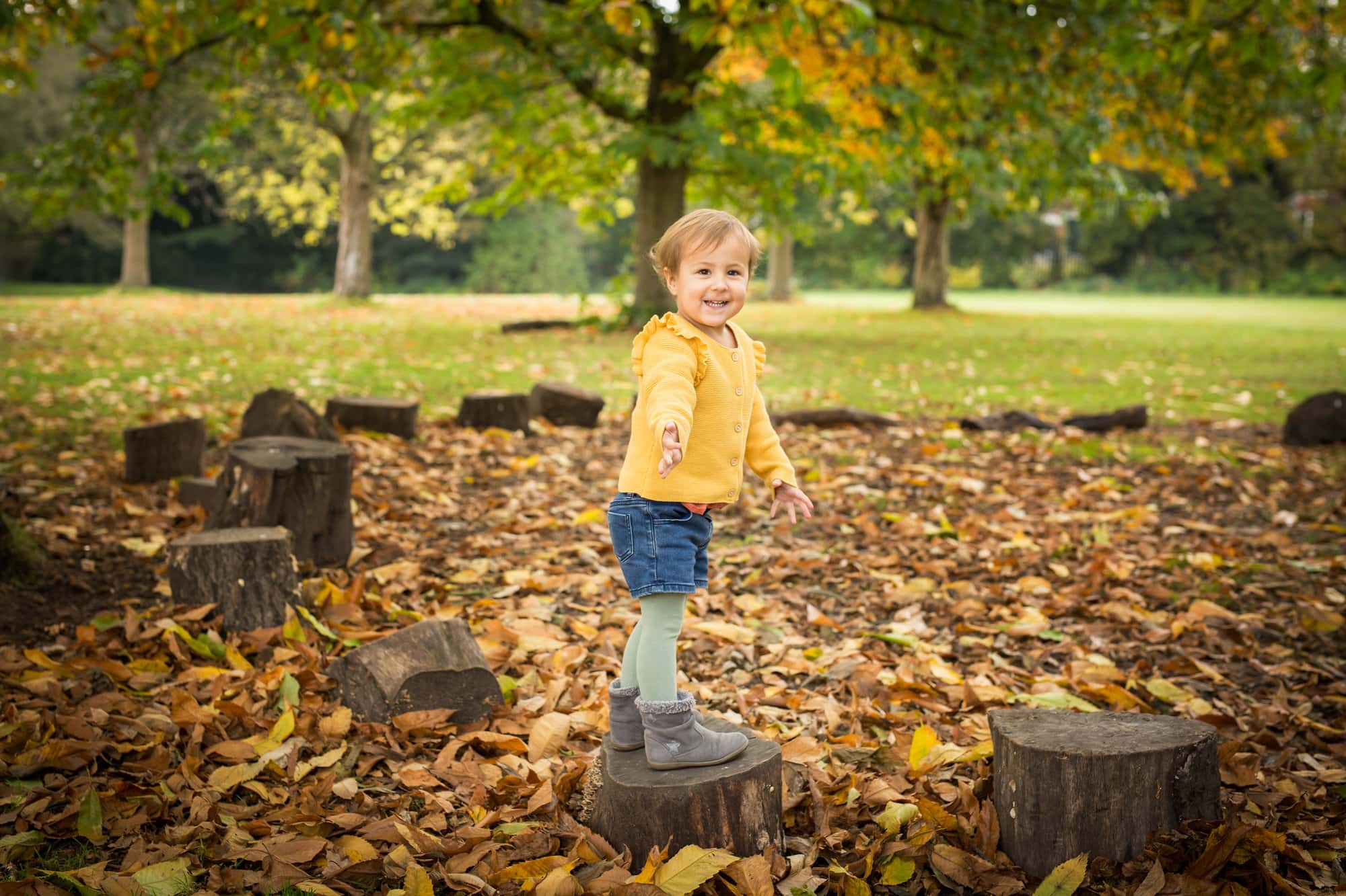 Toddler playing in Autumn leaves in mini session photoshoot in Beckenham Place Park taken by Bromley photographer
