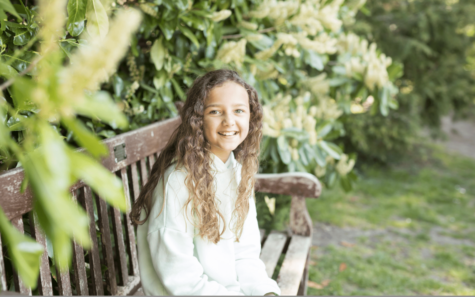 Spring photo of girl sat on bench in Kelsey Park