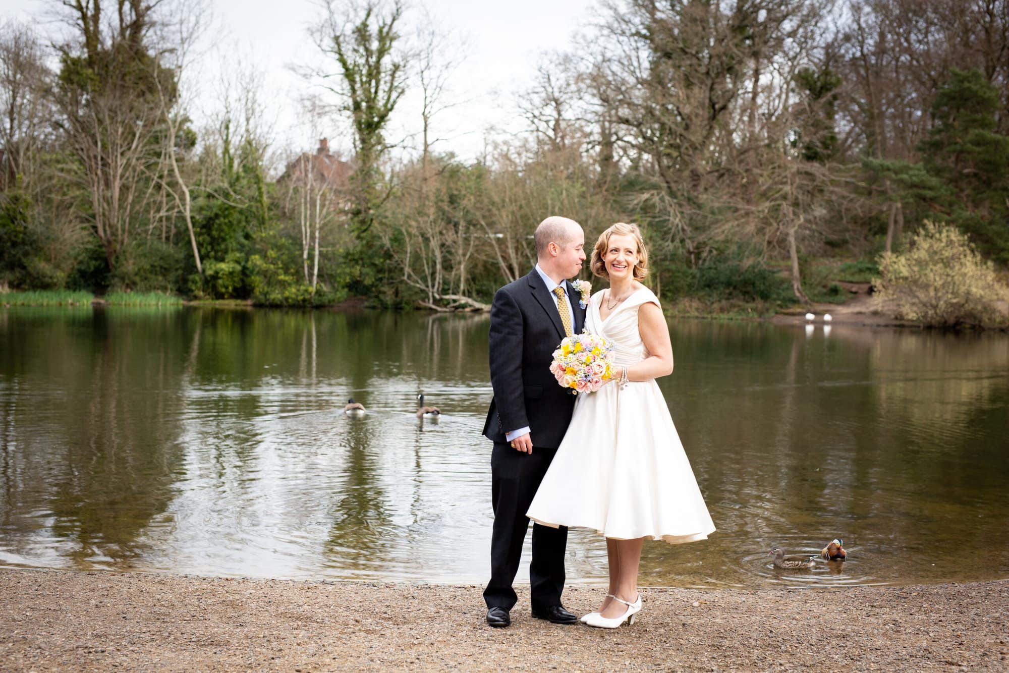 bride and groom standing by Keston Ponds on their wedding day
