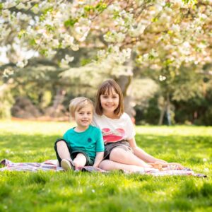 Brother and sister sitting on blanket in Spring time under blossom in photoshoot in Bromley