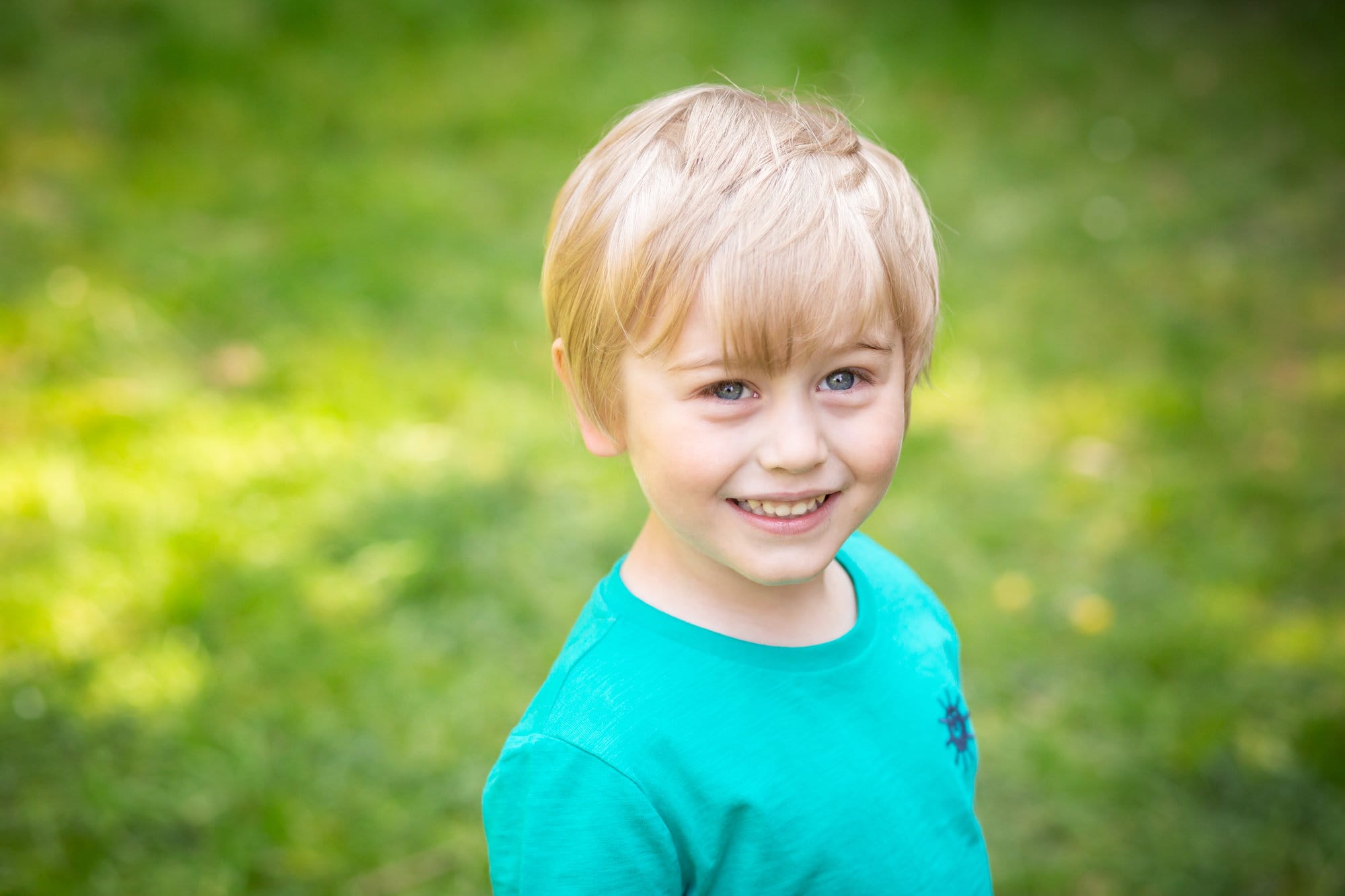 Young boy smiling outside in park in Spring family photoshoot taken by Bromley photographer Tessa Clements