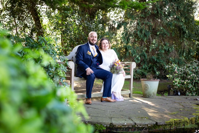 bride and groom sat on bench colour photo taken by Bromley wedding phototgrapher