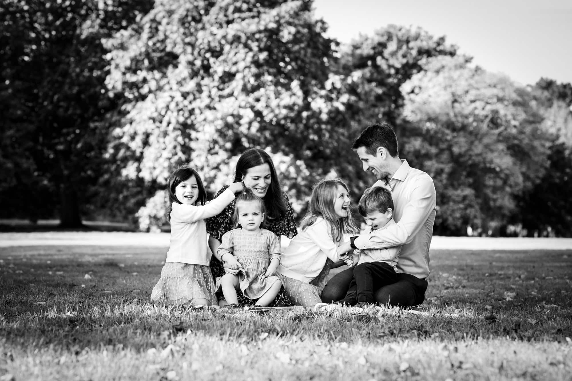 Family laughing and smiling in black and white outdoor photo taken by Beckenham family photographer