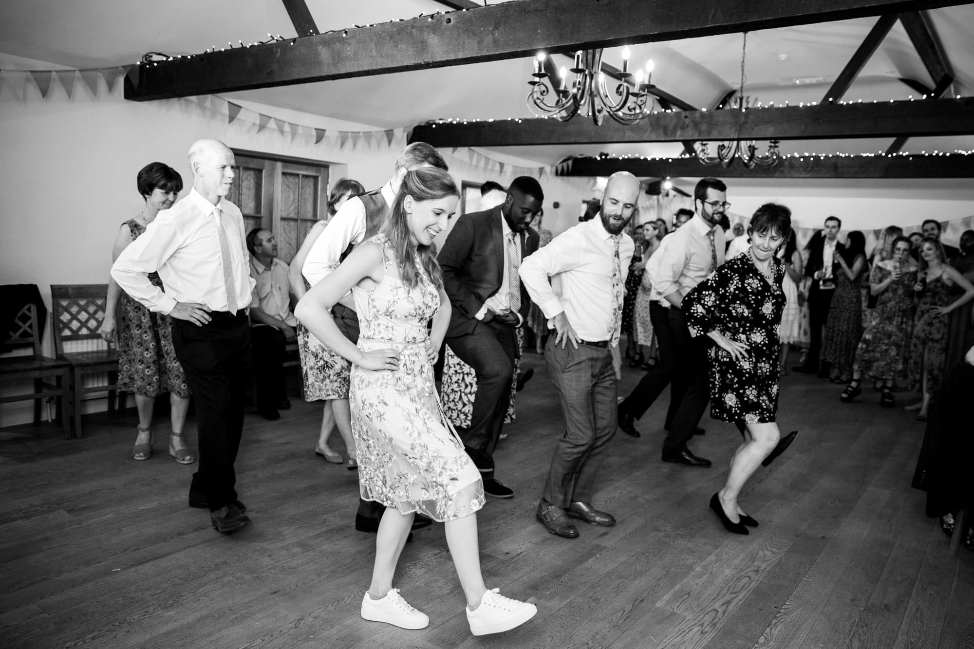 Bride and guests in black and white wedding photography image in Bromley of group line dance