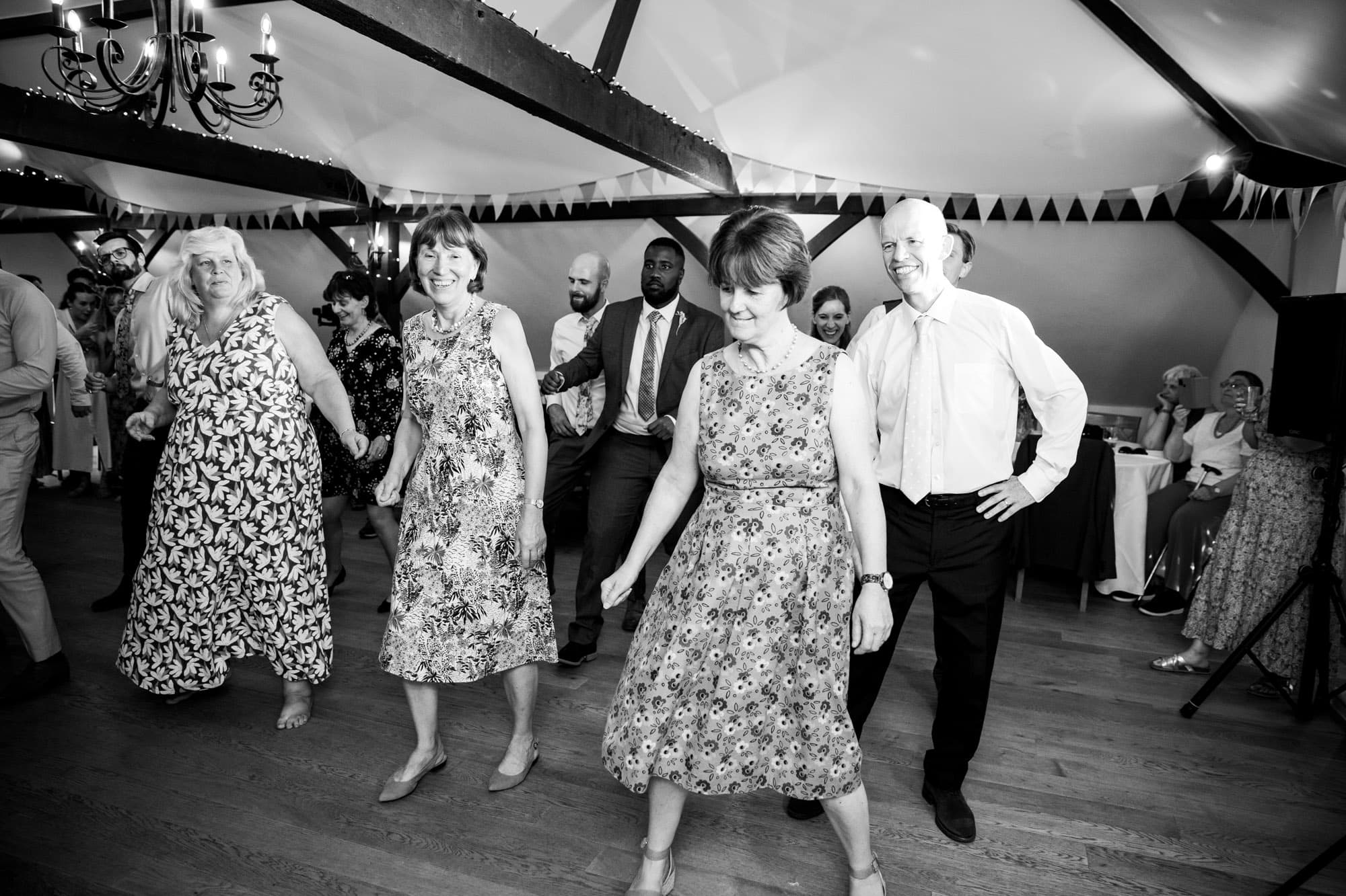 Black and white photo of guest performing group dance at Oaks Farm weddings taken by Bromley wedding photographer