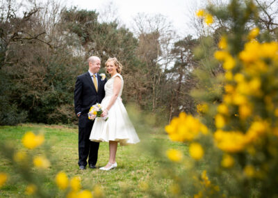 Wedding photo of Bride and groom smiling among yellow flowers at Keston Ponds taken by Beckenham Wedding Photographer
