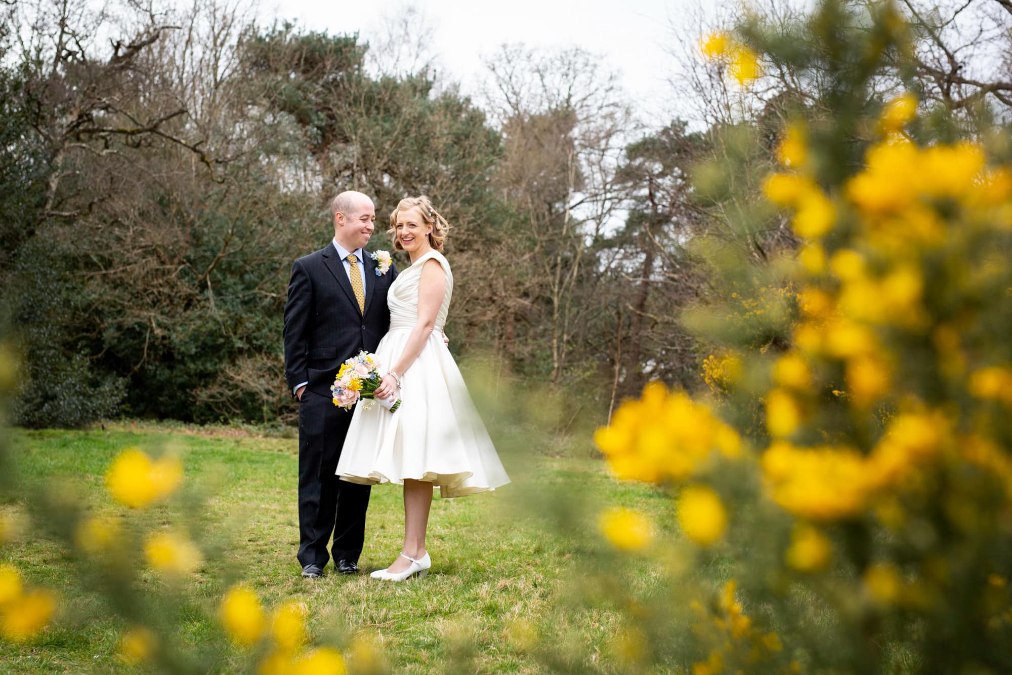 Wedding photo of Bride and groom smiling among yellow flowers at Keston Ponds taken by Beckenham Wedding Photographer