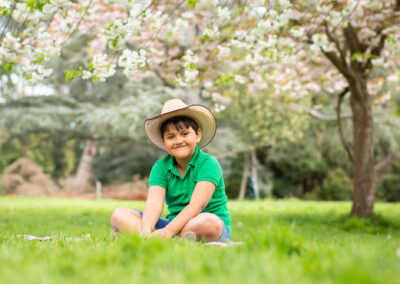 boy sat on grass among spring blossom with cowboy hat on taken by Beckenham family photographer