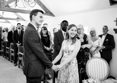 Black and white wedding image at Oaks Farm Weddings of couple saying their vows while holding hands and smiling