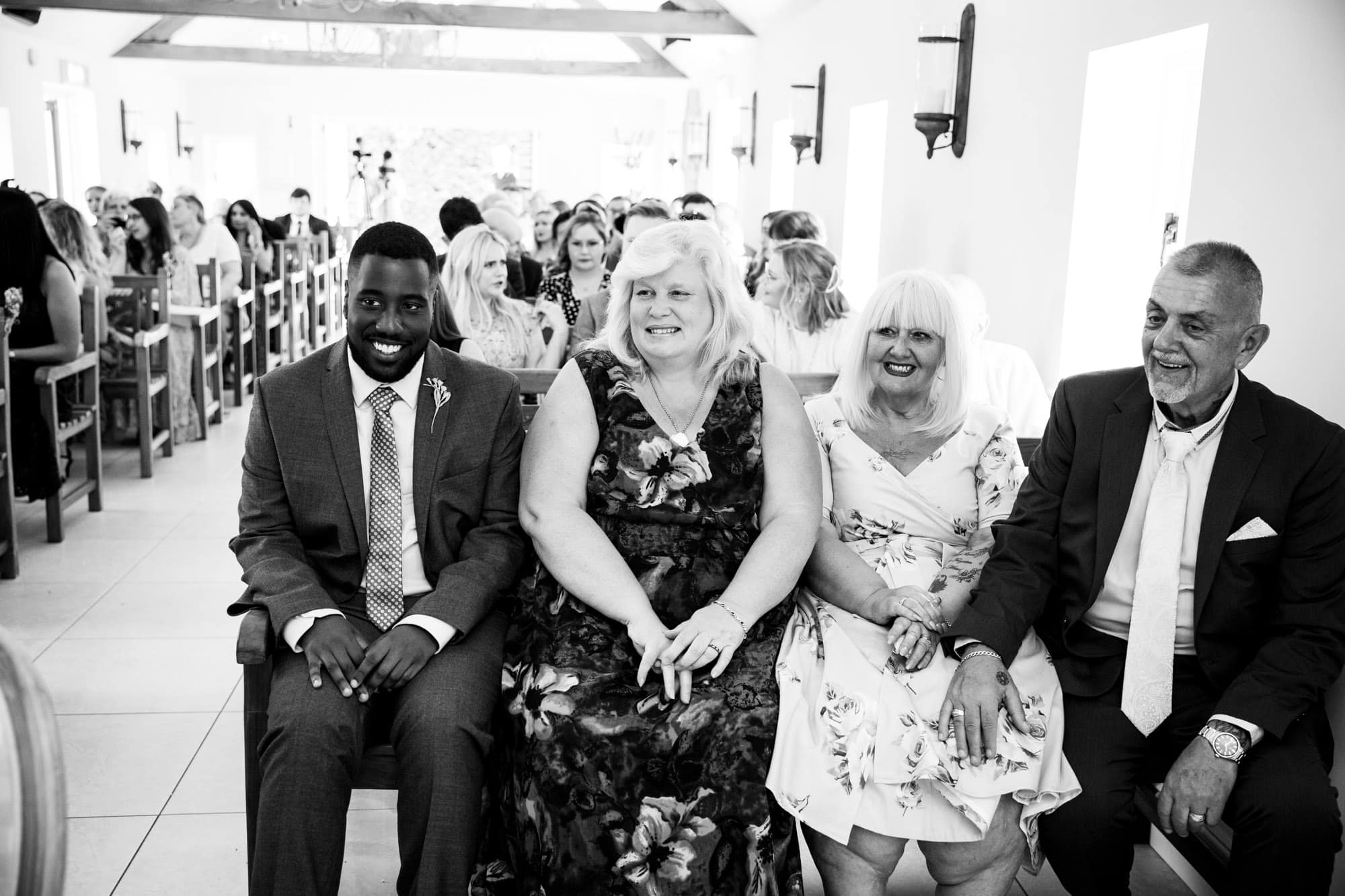 Black and white photo of guests at wedding ceremony at Oaks Farm Weddings taken by Tessa Clements