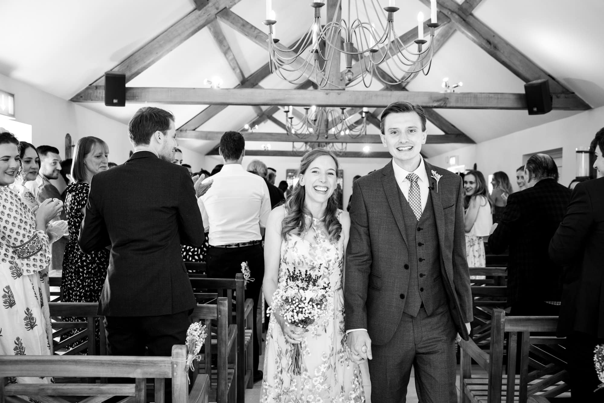 Newly married couple holding hands and walking out from ceremony wedding at Oaks Farm Weddings venue in Bromley wedding photography image