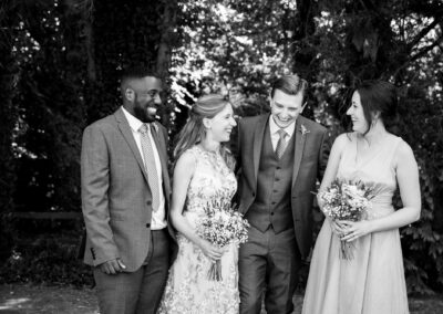 Bromley wedding photographer image in black and white of couple and guests laughing and smiling at Oaks Farm Weddings venue