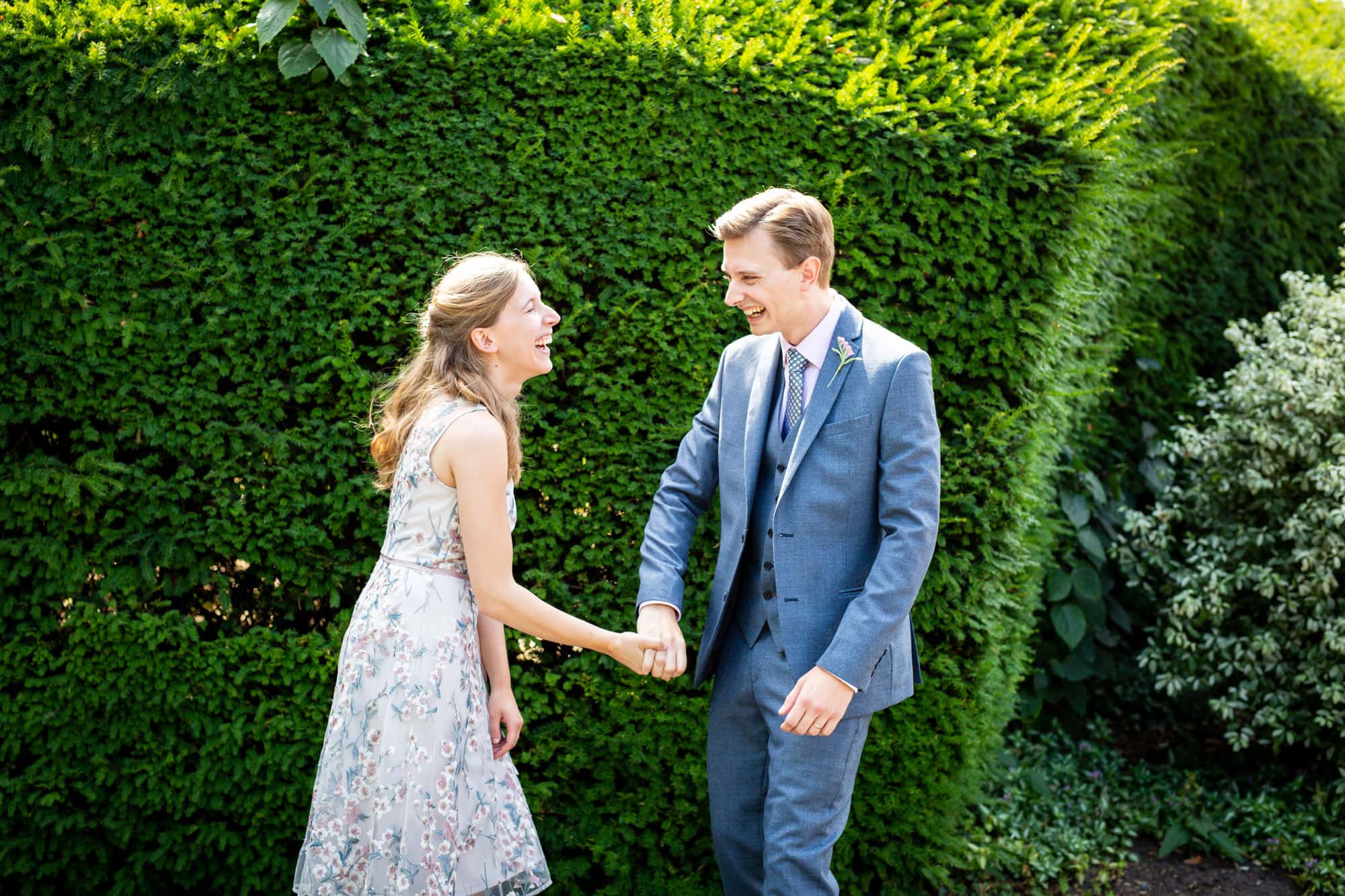 couple laughing surrounded by greenery in Bromley wedding photoshoot at Oaks Farm Weddings