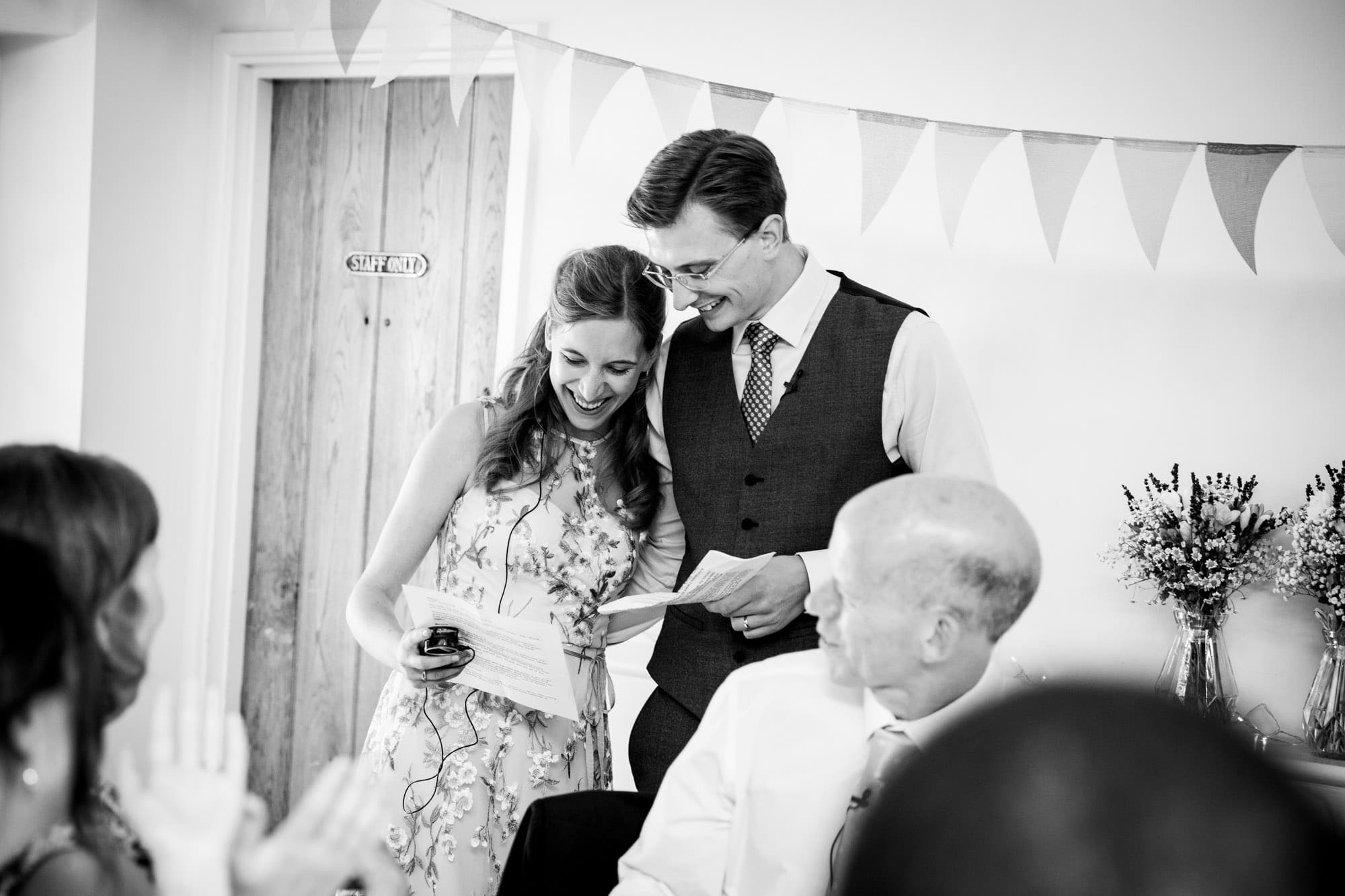 Couple reading out their joint speech in black and white wedding photo by Bromley wedding photographer at Oaks Farm Weddings