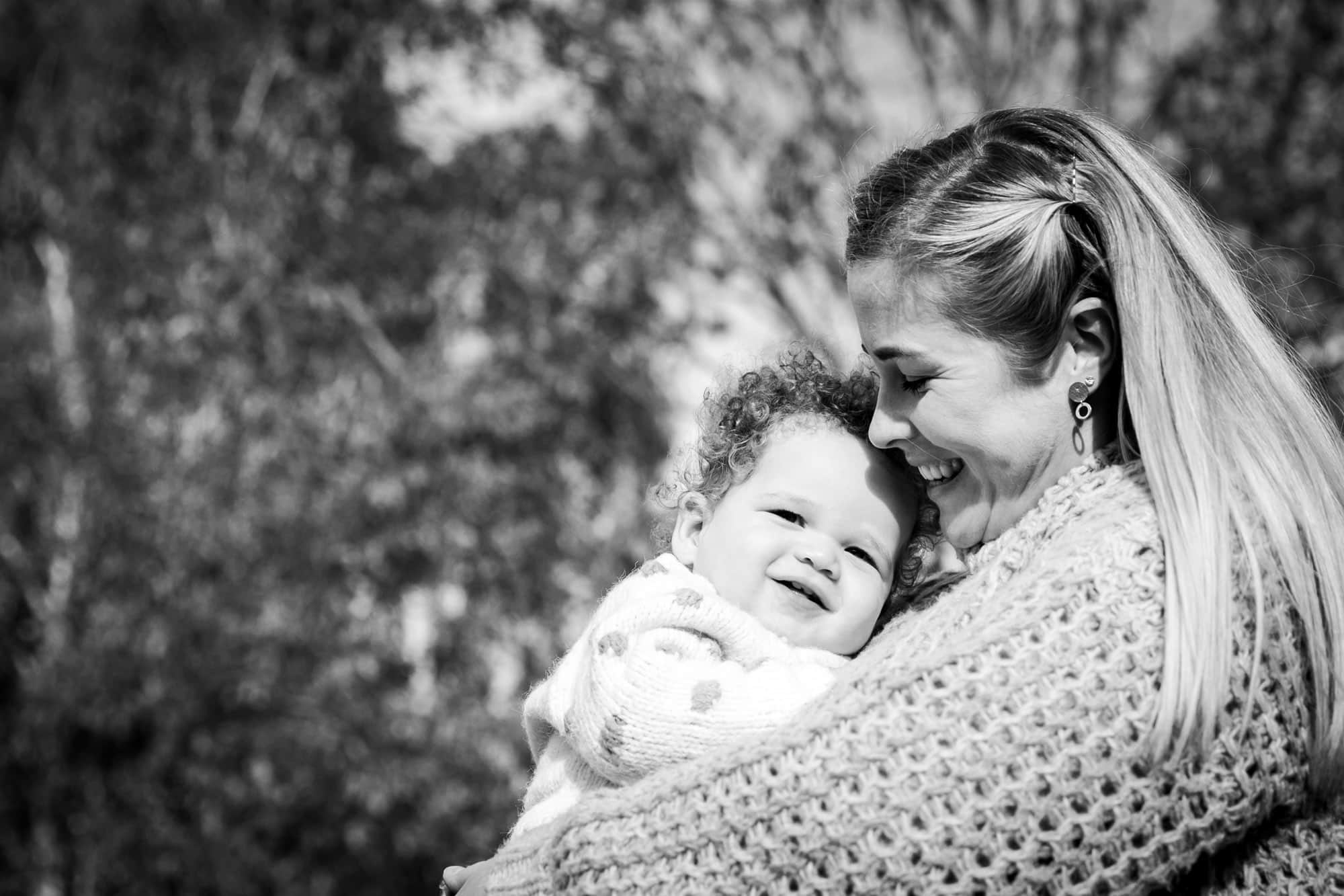 Mum cuddling baby in arms outside in park in black and white Beckenham photoshoot