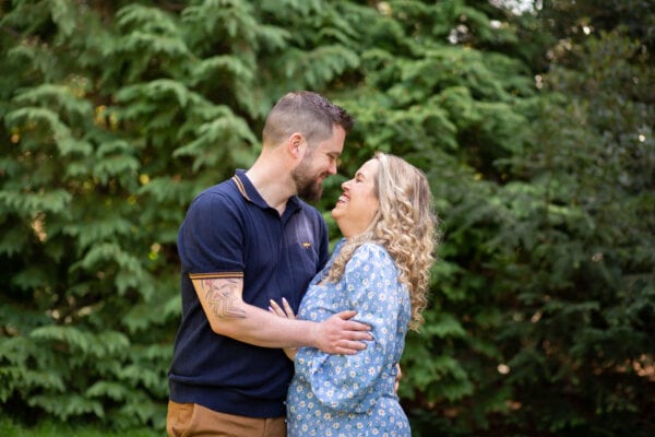 couple cuddling outside by trees by Bromley family photographer