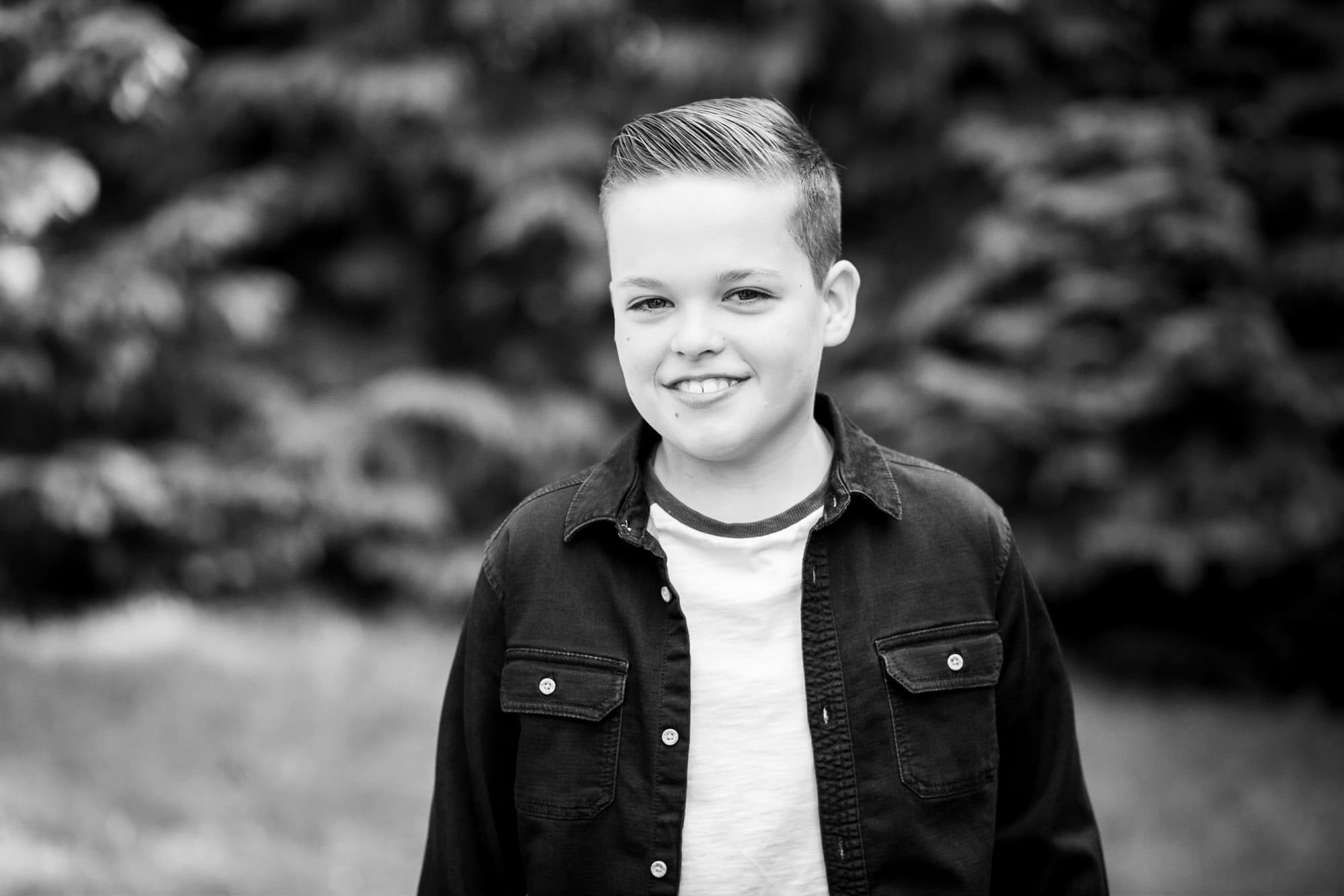 Close up black and white photo of boy outside wearing dark shirt by Bromley family photographer