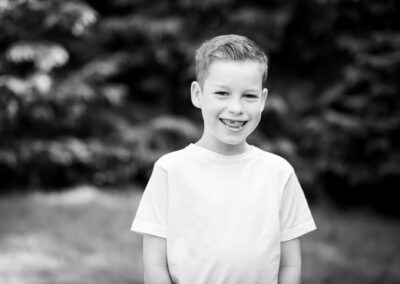 Close up black and white photo of boy outside wearing white t-shirt by Bromley family photographer